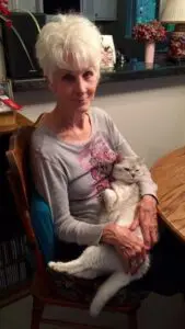 A woman sitting at the table with her cat.