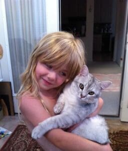 A girl holding a cat in her arms.