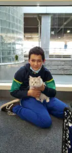 A boy holding a cat while sitting on the ground.