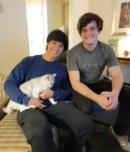 Two people sitting on a couch with a cat