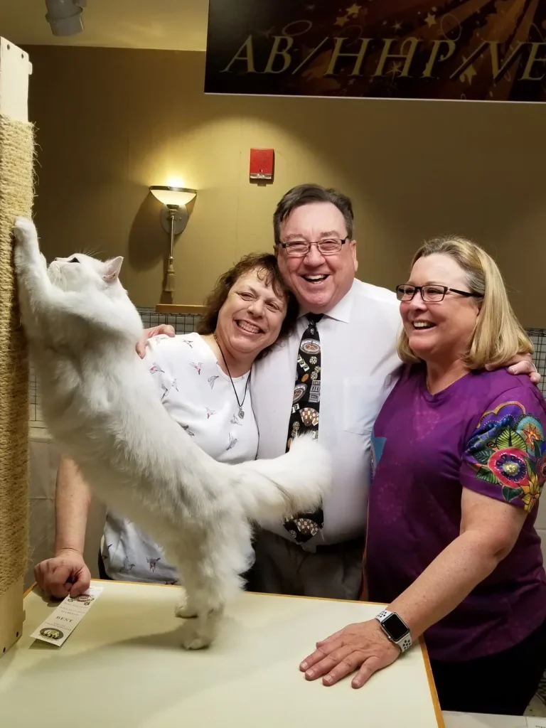 A group of people standing around with a cat.